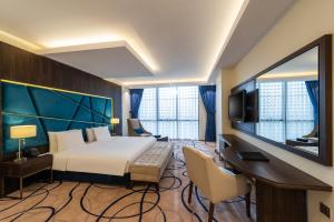 リヤドにあるWarwick Riyadh Al Wezaratのベッド、デスク、テレビが備わるホテルルームです。