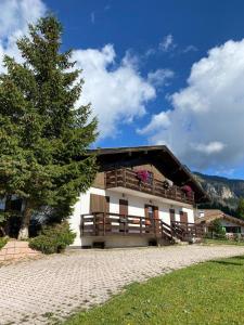 un edificio con un árbol delante de él en Chalet Relax, en Pozza di Fassa