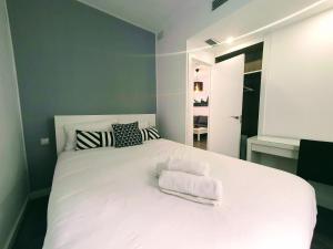 um quarto com uma cama branca e toalhas em Recien renovado junto a Santa Justa y el centro em Sevilha