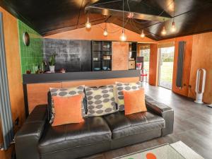 a living room with a leather couch and a kitchen at The Tractor Shed in Worcester