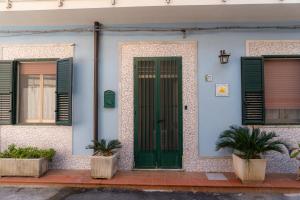 Stella Maris Marzamemi Apartments في مارزاميمي: منزل فيه باب أخضر و نافذتين