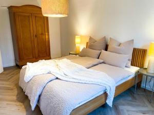 sypialnia z dużym łóżkiem z białą pościelą i poduszkami w obiekcie Ferienwohnung Ava No3- Heiligkreuztal 2-3 Personen w mieście Heiligkreuztal