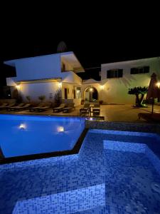 a pool in front of a house at night at Oasis Beach Club in Kavos