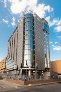 a large glass building with flags in front of it at Warwick Riyadh Al Wezarat in Riyadh