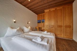 1 dormitorio con 2 camas, sábanas blancas y techos de madera. en Appartement Spielberg, en Saalbach Hinterglemm