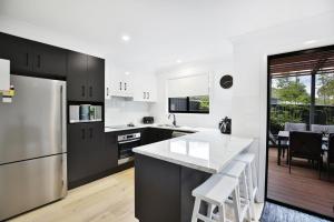 a kitchen with black cabinets and white appliances at Zen @ Culburra - Pet Friendly - 8 Mins to Beach in Culburra Beach