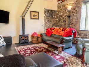 uma sala de estar com um sofá e um fogão a lenha em Old Spot Cottage em Goodwick