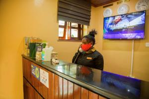 a woman with a red mask standing at a counter at Fort Motel in Fort Portal