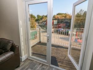uma porta de vidro deslizante com vista para um deque em The Apartment at Plas Yr Eithin em Amlwch
