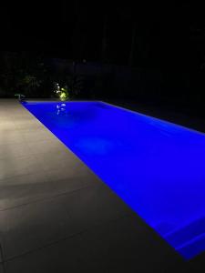 una piscina blu viene illuminata di notte di Beautiful large home available in tropical north Queensland a Port Douglas