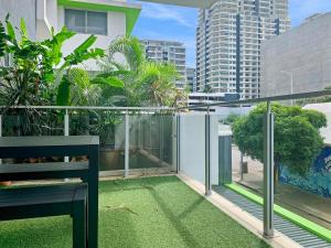 ダーウィンにあるDarwin City Chic@Kube Apartmentsの緑の芝生とベンチ付きのバルコニー