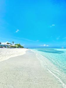 a white beach with a palm tree and the ocean at Beach Walk Villa Maldives in Gulhi
