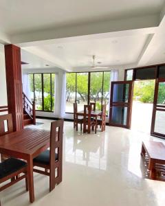 a dining room with tables and chairs and windows at Beach Walk Villa Maldives in Gulhi