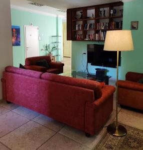 een woonkamer met een rode bank en een televisie bij Hostel Roks in Haifa