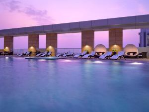 a pool on the roof of a building with chairs at Dusit Thani Abu Dhabi in Abu Dhabi
