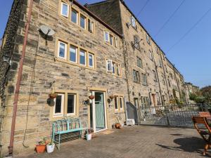 an old brick building with a green door on it at Kingfisher Cottage in Holmfirth