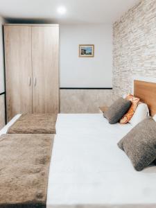 1 dormitorio con 2 camas y pared de ladrillo en Vivienda de Uso Turístico MARINA LUXURY, en Padrón