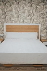 a bedroom with a white bed and a wall at Vivienda de Uso Turístico MARINA LUXURY in Padrón