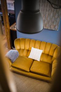 a yellow couch with two white pillows on it at Appartements et Séminaires Griotte et Cannelle in Bergbieten