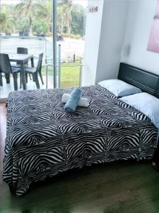een bed met een zwart-wit dekbed met een knuffel bij Apartamento en BalaBeach María Chiquita in front of the beach 2hab in Colón
