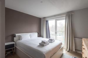 a bedroom with a bed with white sheets and a window at GuestReady - Cosy 2BR Home in Vibrant Angel in London