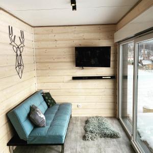 sala de estar con sofá azul y TV en Małe Formy - drewniany domek w górach z balią en Kamienna Góra
