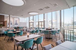 a restaurant with tables and chairs and large windows at Radisson RED, Oslo Airport in Gardermoen