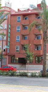 a red building with a palm tree in front of it at Hotel Azahar in Sagunto