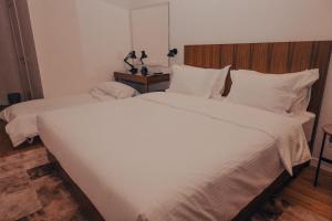 a bedroom with a large white bed with a wooden headboard at Hotel Theatro- City Center in Tirana