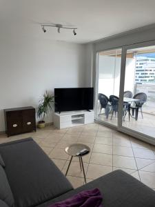 ein Wohnzimmer mit einem TV, einem Tisch und Stühlen in der Unterkunft Appartamento 2,5 con piscina nel CUORE di Locarno 463 in Locarno