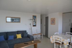 Una sala de estar con un sofá azul y una mesa. en FACE MER et PLAGE, entre SAINT MICHEL et SAINT BREVIN, en Saint-Michel-Chef-Chef