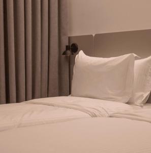 1 cama con sábanas y almohadas blancas y lámpara en Hotel Theatro- City Center en Tirana