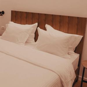 ein weißes Bett mit weißen Kissen und einem Kopfteil aus Holz in der Unterkunft Hotel Theatro- City Center in Tirana