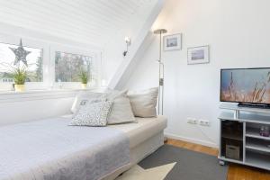 um quarto branco com uma cama e uma televisão de ecrã plano em Haus Waldfrieden Wohnung 1 em Haffkrug