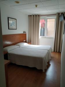 a bedroom with a large white bed and a window at Hotel Besaya in Torrelavega
