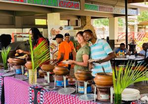um grupo de pessoas à volta de uma mesa com comida em Panone Hotels - King'ori Kilimanjaro Airport em Moshi