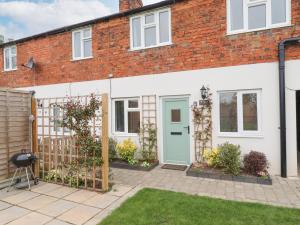 a house with a blue door and a fence at Primrose Cottage in Market Harborough