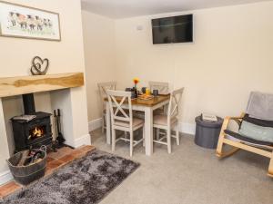 a living room with a table and a fireplace at Primrose Cottage in Market Harborough