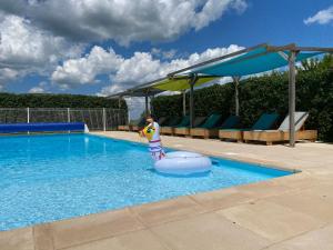 a swimming pool with a inflatablelatable dog in the water at Gîte Bellevue - cosy huisje op vakantiepark in Jayac