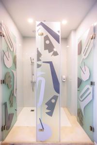 a bathroom with a glass door with a mural of toilets at Musical Hostel in Albufeira