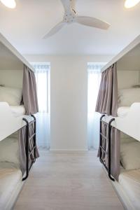 2 camas num quarto com uma ventoinha de tecto em Musical Hostel em Albufeira