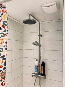 a shower in a bathroom with white tiles at Nommen Fishing Cottages in Vetlanda