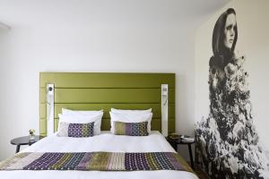 デュッセルドルフにあるホテル インディゴ デュッセルドルフ ヴィクトリアプラッツのベッドルーム1室(緑のヘッドボード付きのベッド1台付)