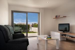 uma sala de estar com um sofá, uma televisão e uma mesa em Boquer Apt em Pollença