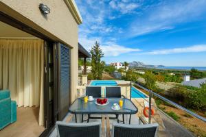 een patio met een tafel en stoelen op een balkon bij Aegean Blue Villa's - All Inclusive & Water park in Kalathos