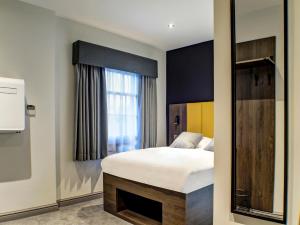 1 dormitorio con cama y ventana en OYO Tamworth Arms Boutique Pub & Hotel, en Tamworth