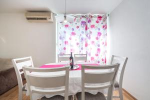 a dining room table with three chairs and a pink curtain at Apartment Lidija in Dubrovnik