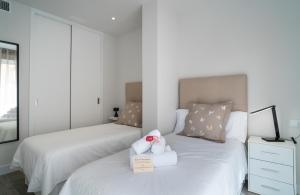 dwa łóżka z ręcznikami i pluszakiem na nich w sypialni w obiekcie AAC Málaga - Apartamento luminoso y nuevo, a 1,3km del centro de Málaga w Maladze