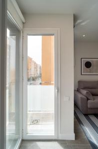 マラガにあるAAC Málaga - Apartamento luminoso y nuevo, a 1,3km del centro de Málagaのリビングルーム(ソファ付)へ続くガラスのスライドドア