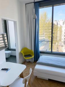 um quarto com uma cama e uma cadeira amarela e uma janela em SMARTments business Berlin City West em Berlim